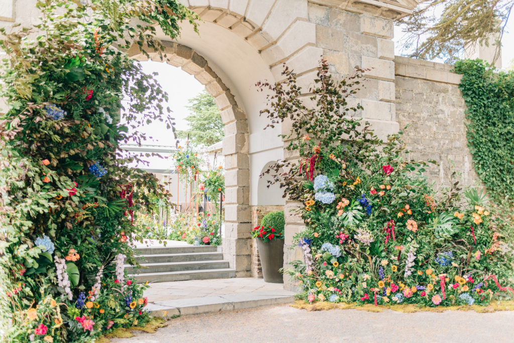 stone archway with floral arch on both sides with bright florals and ivy