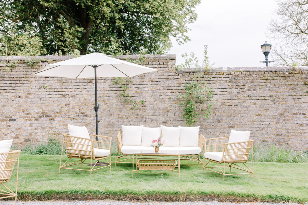 rattan couch and chairs with white cushions and a rattan lawn table on grass