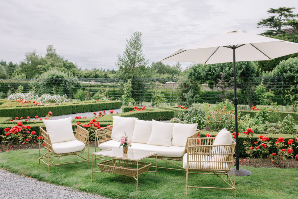 garden with rattan lawn furniture and white cushions and a white umbrella