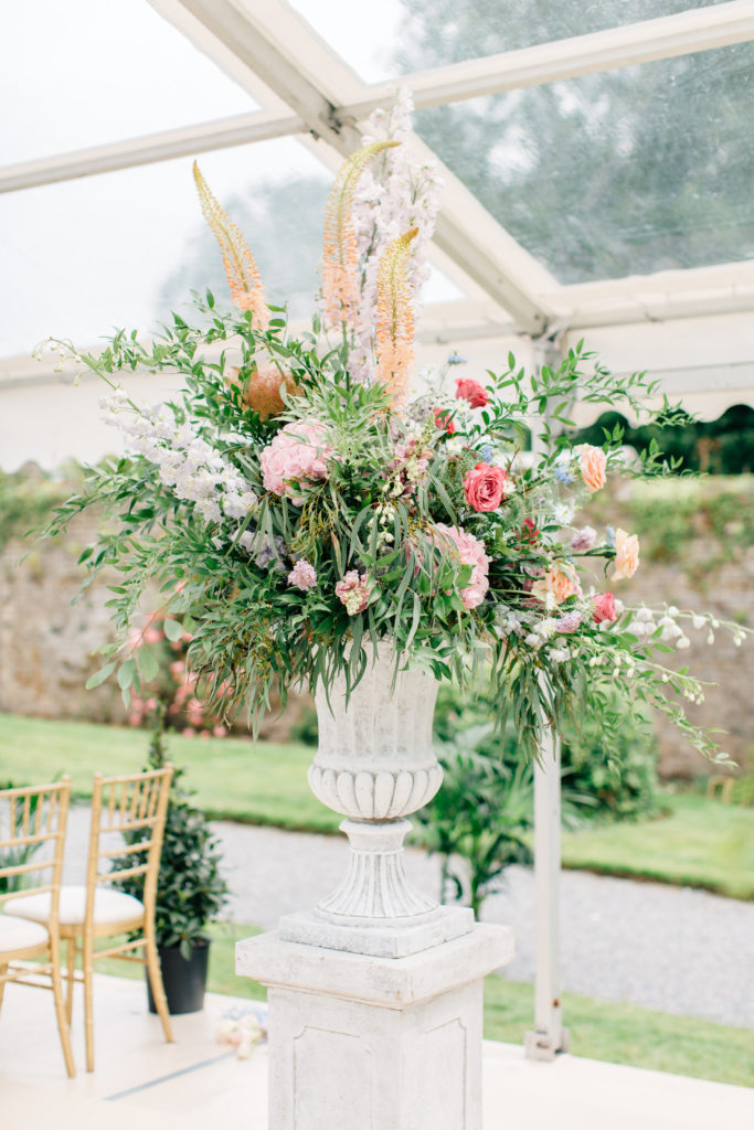 large stone pedestal urn with pastel pink blue purple and peach flowers and hot pink accent flowers