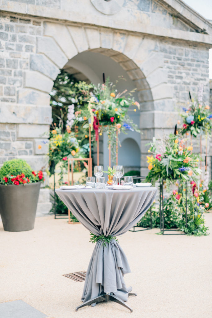 pod table with gray linens and floral arrangements and organic greenery